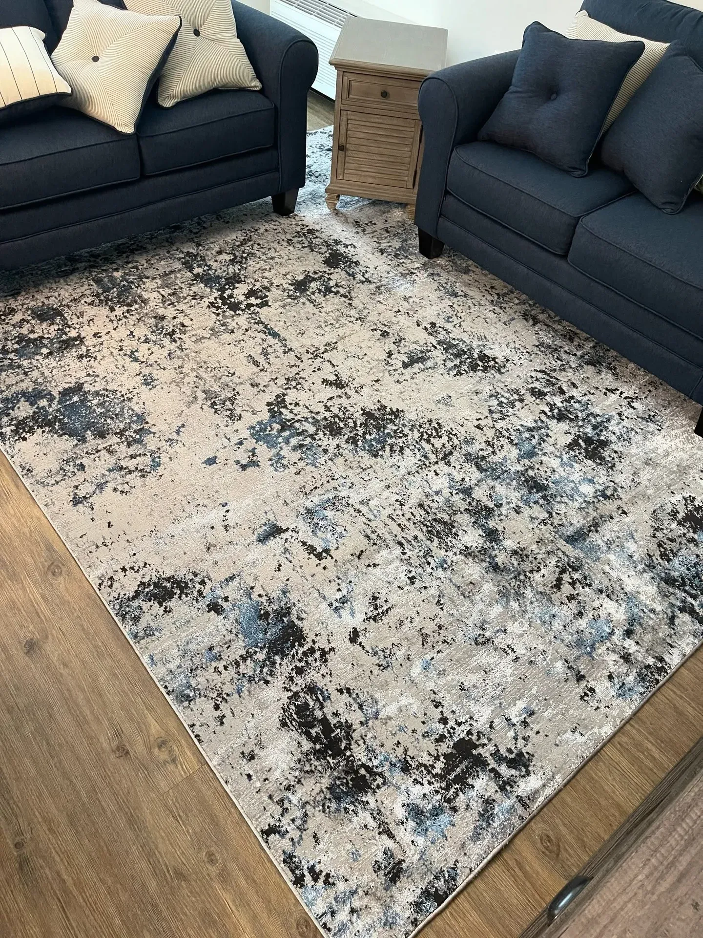 Abstract navy and cream area rug between navy sofas on plank flooring