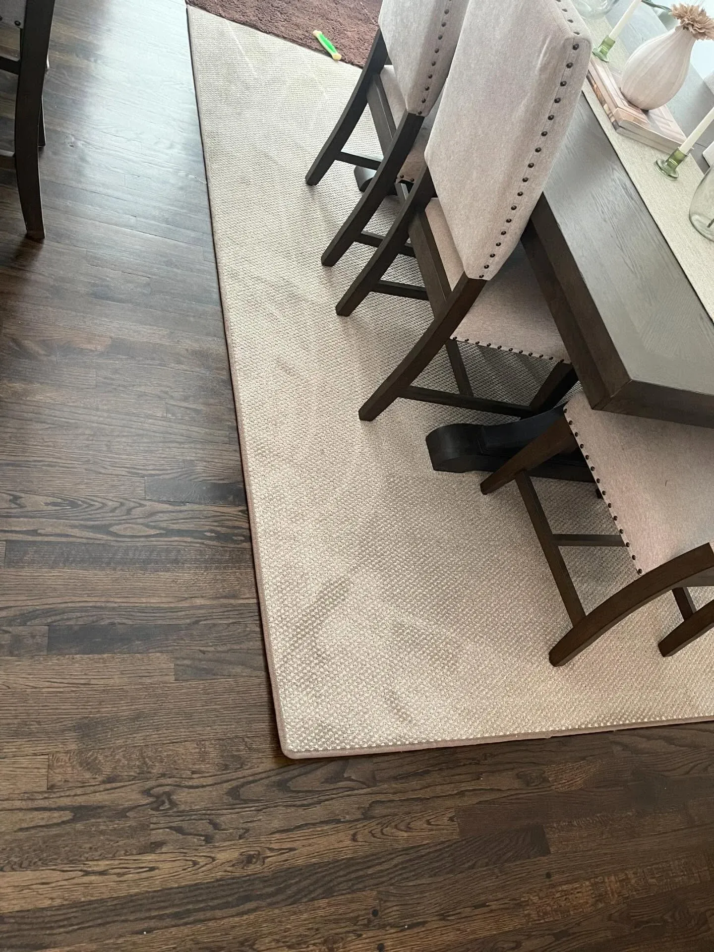 Cream bound area rug under a dining table on dark hardwood floors
