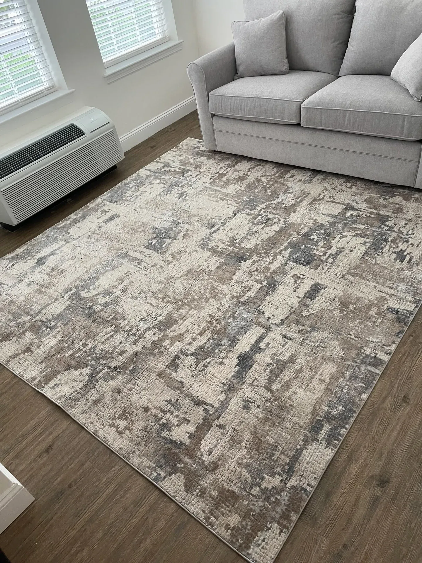 Ivory and grey abstract area rug under a grey sofa on plank flooring
