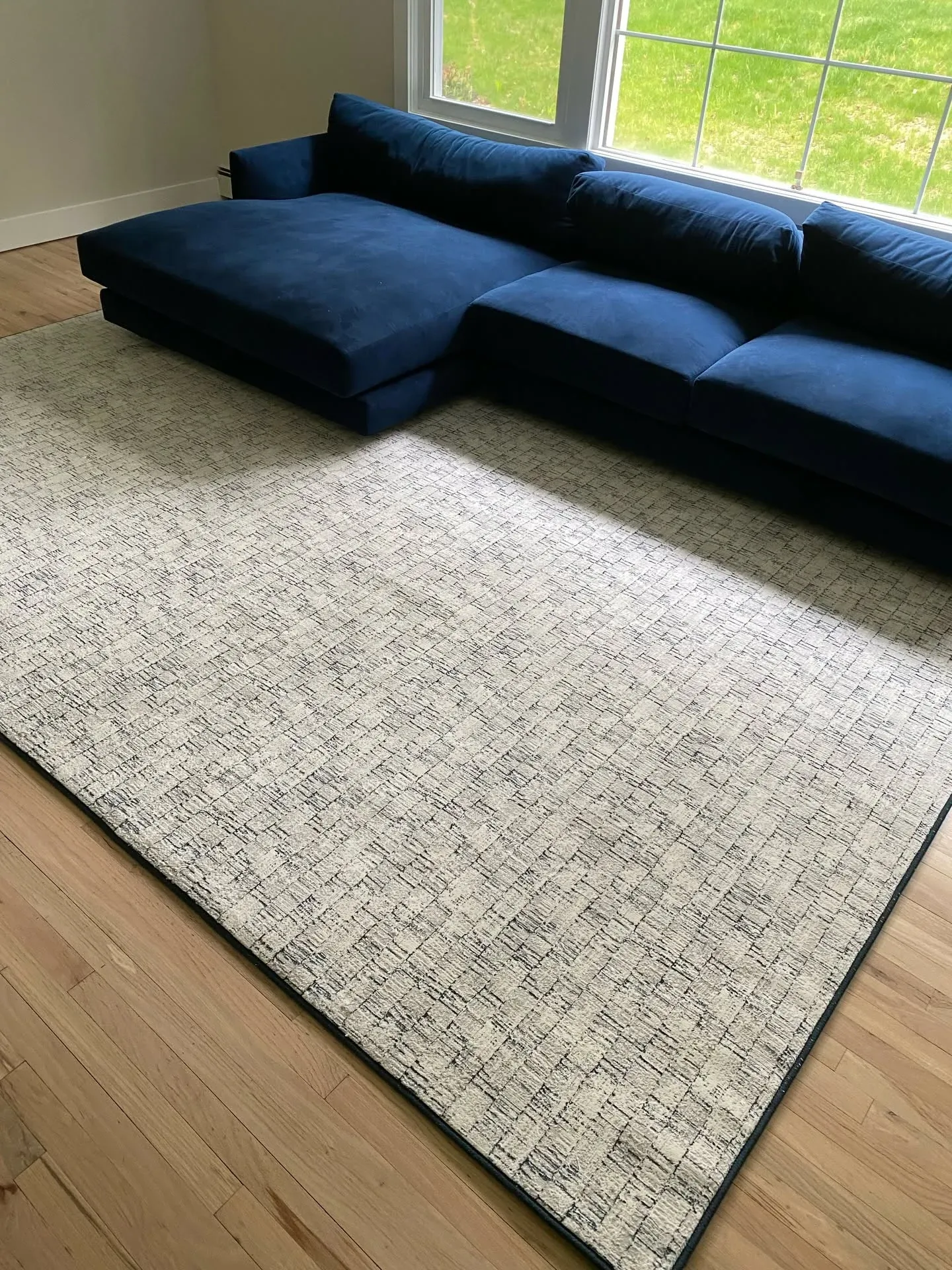 Ivory and grey area rug in a sunlit living room with a navy sectional