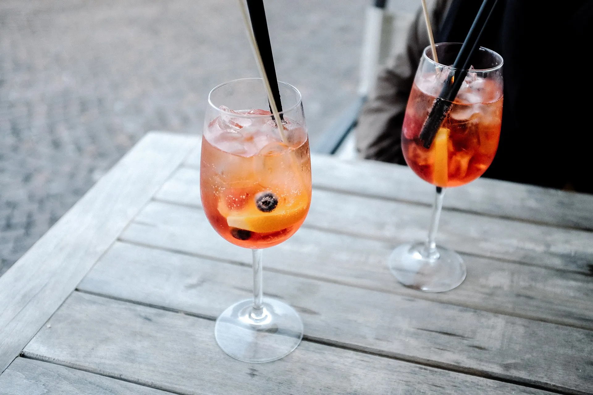 Two spritz cocktails on a weathered wooden outdoor table