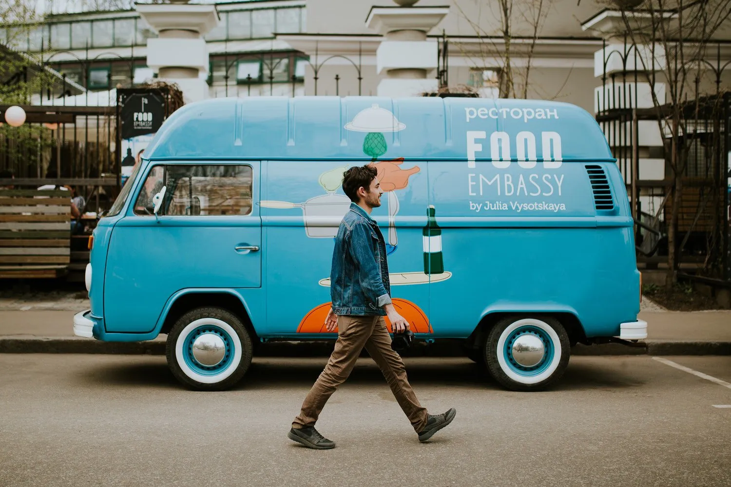 Man walking past a blue vintage food truck van on a city street