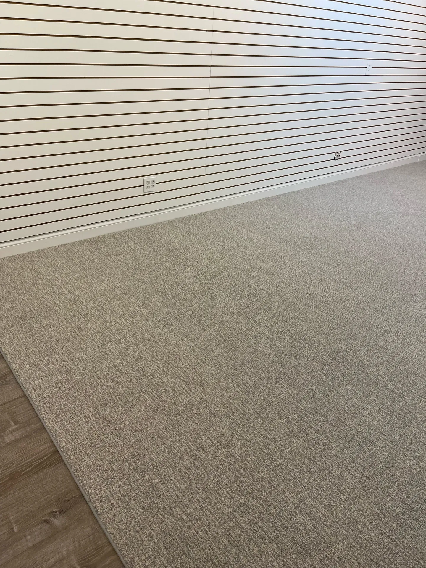 Beige carpet installed in a finished basement with a slat accent wall