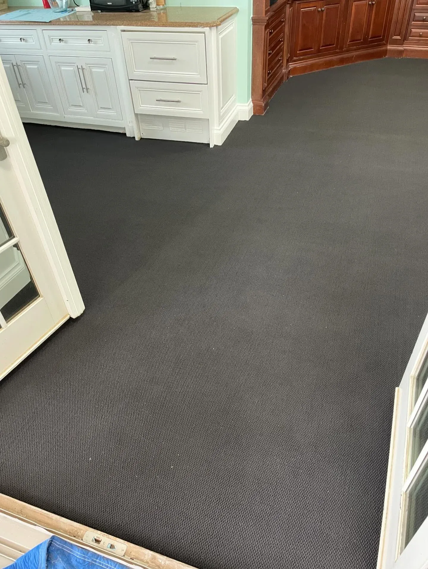 Dark grey wall-to-wall carpet installed beside built-in cabinetry
