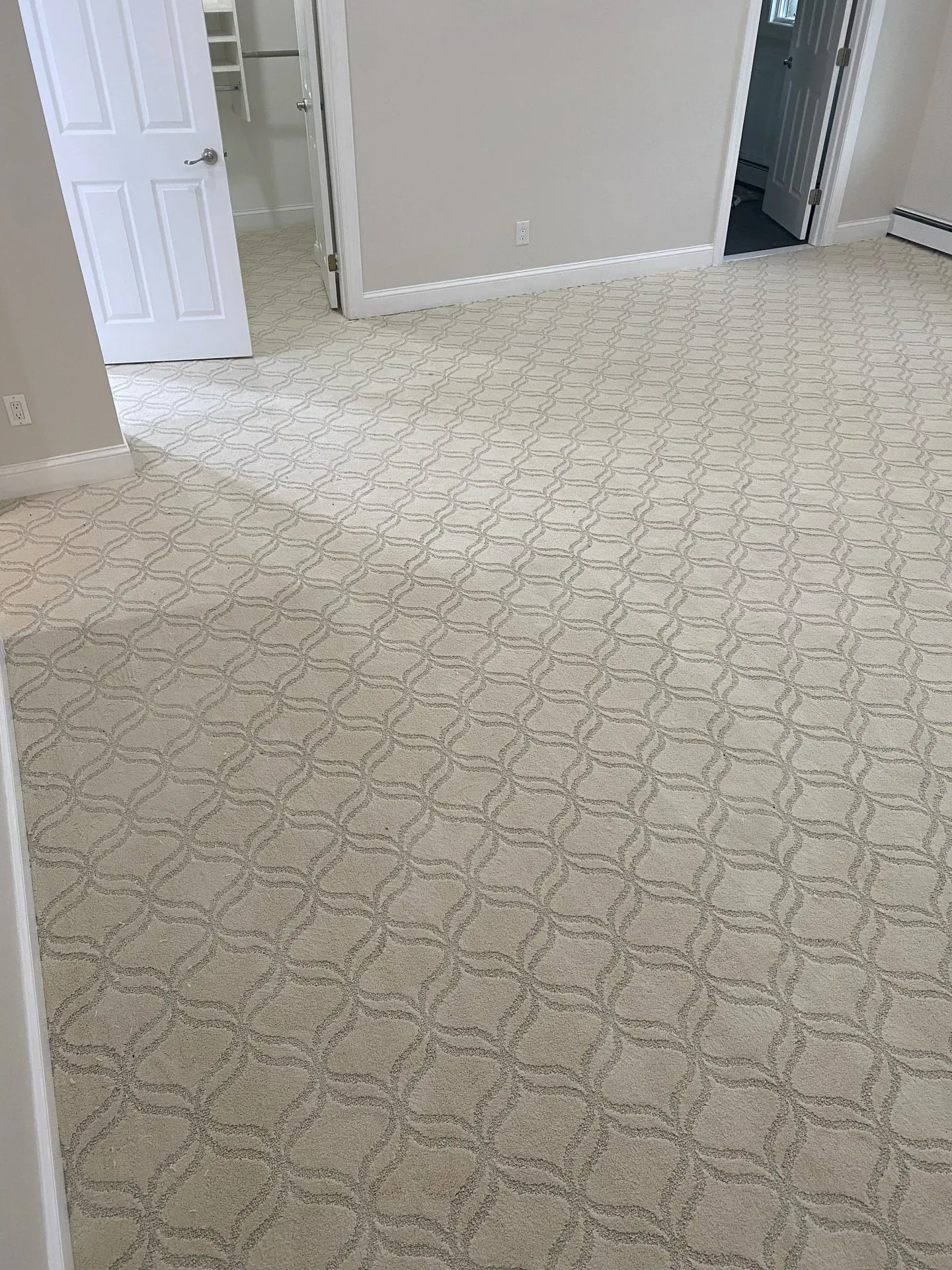 Geometric lattice-pattern carpet installed wall to wall in a bedroom