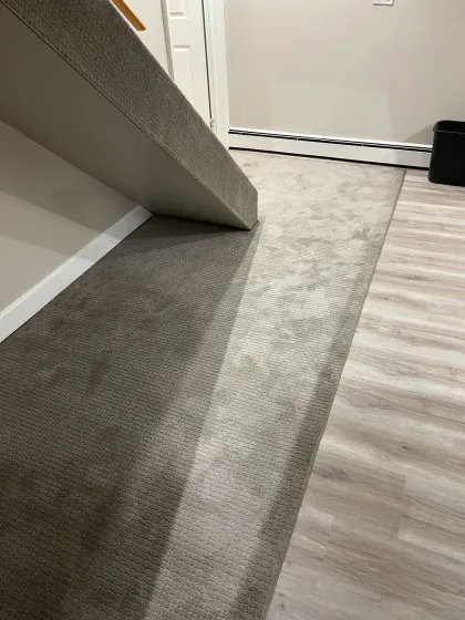 New carpet being installed over a light plank floor