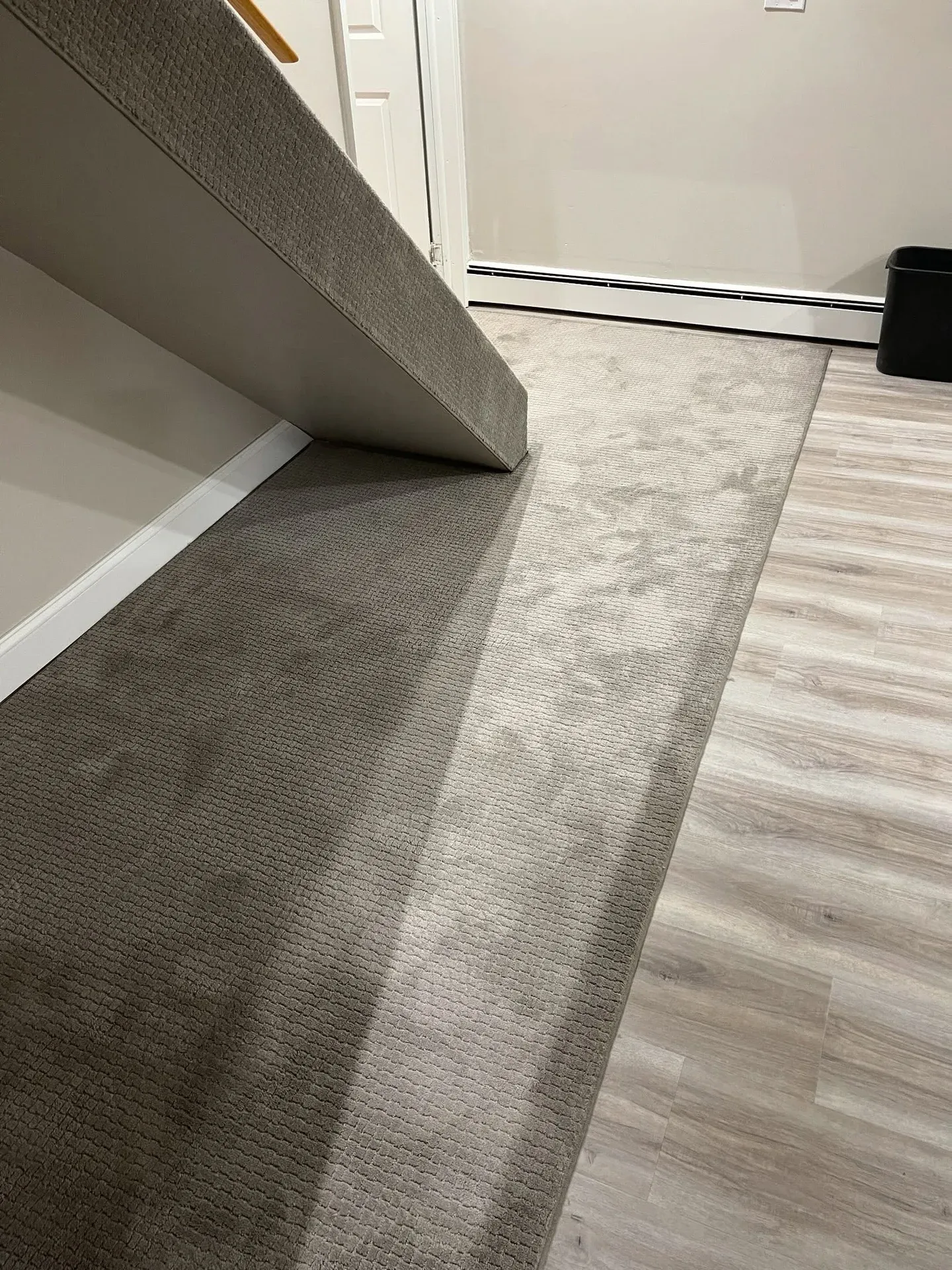 New carpet being installed over a light plank floor