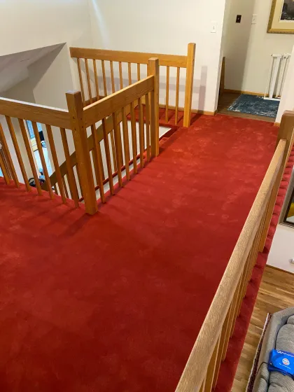 Red carpet installed around an oak stair railing