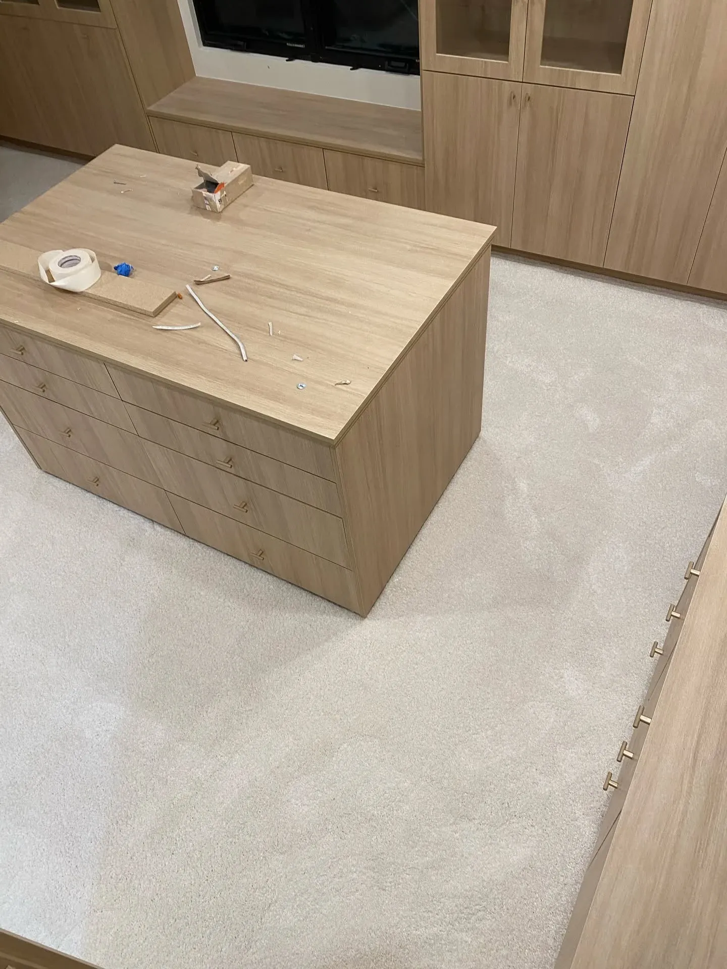 Cream carpet in a walk-in closet, with a tape measure on the cabinet island
