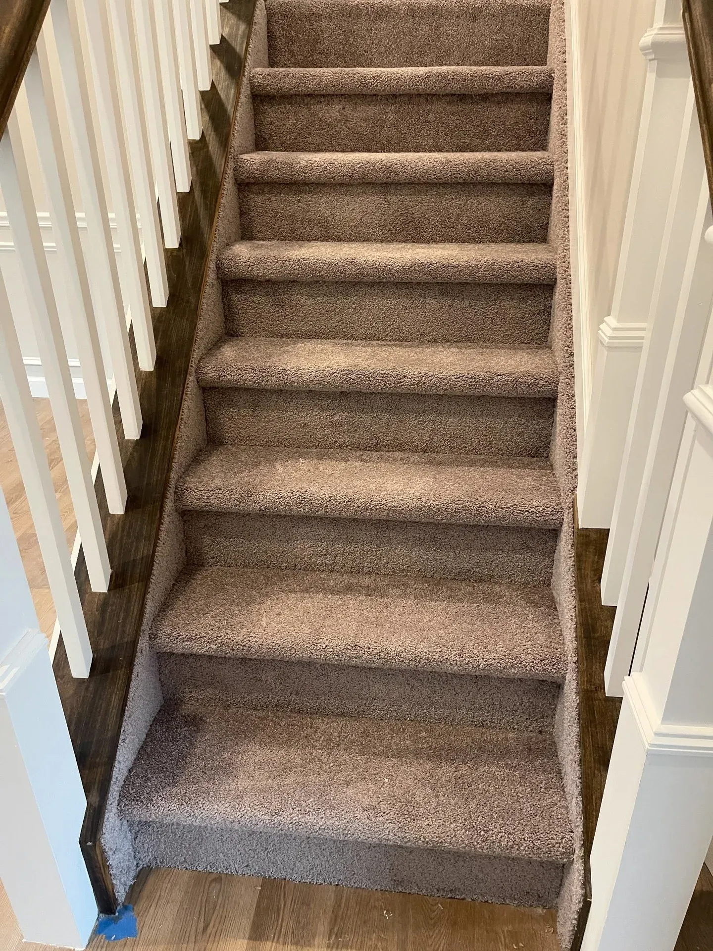 Brown carpet installed on a staircase with white balusters