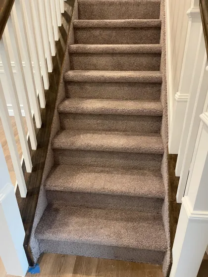 Brown carpet installed on a staircase with white balusters