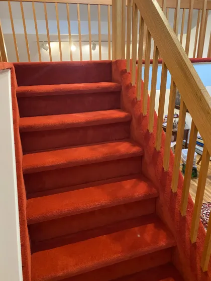Red carpet installed on a staircase with oak railings