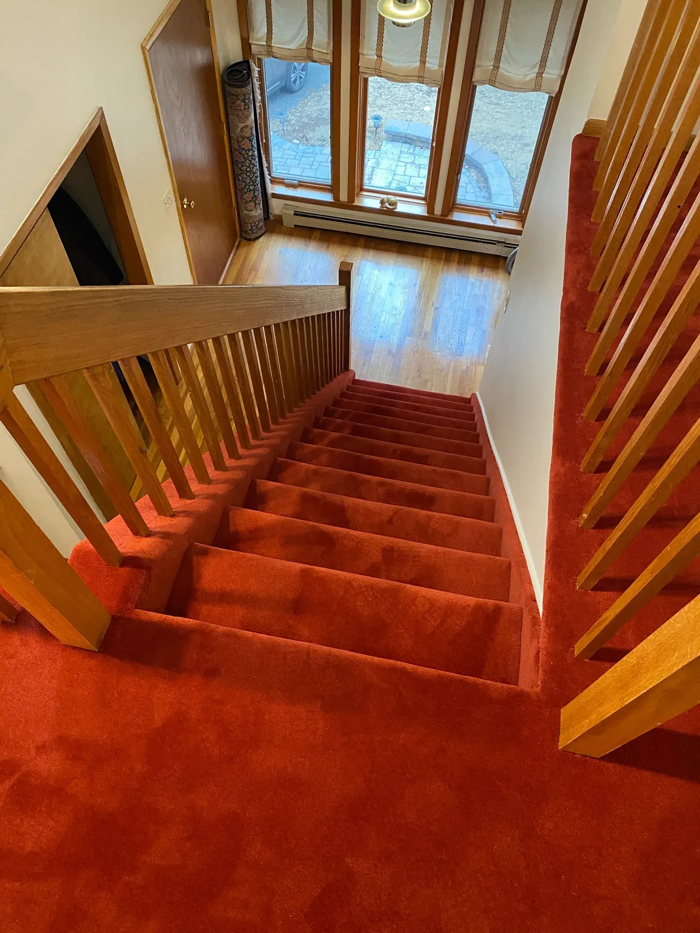 Red carpet installed down a staircase with oak railings