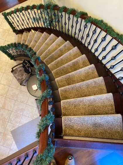 Curved staircase runner above a tiled entry foyer