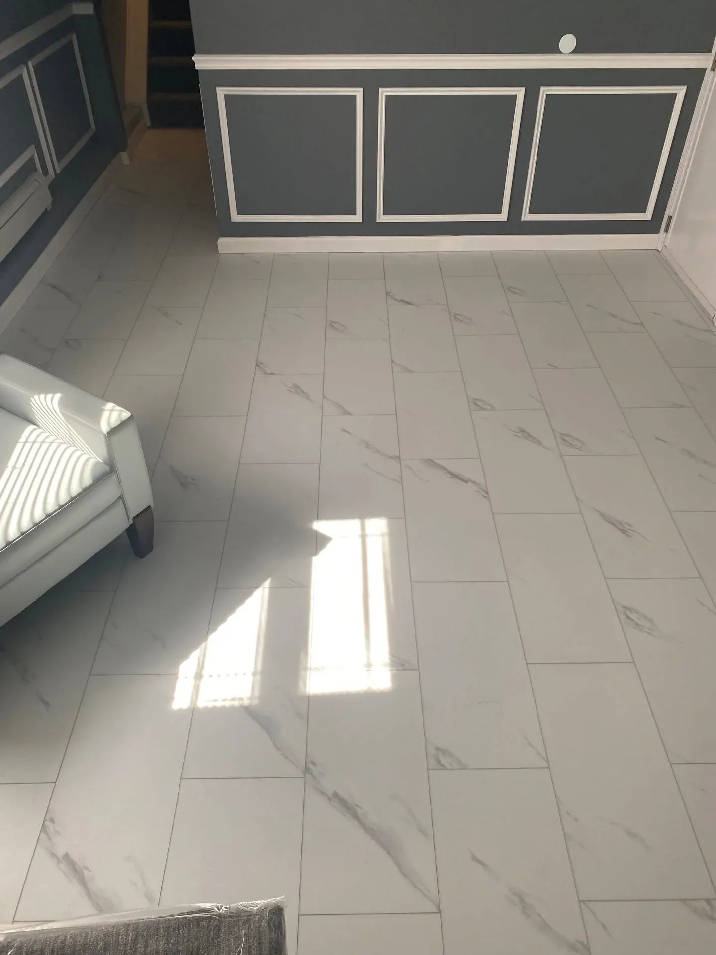 Marble-look tile floor below grey wainscoting